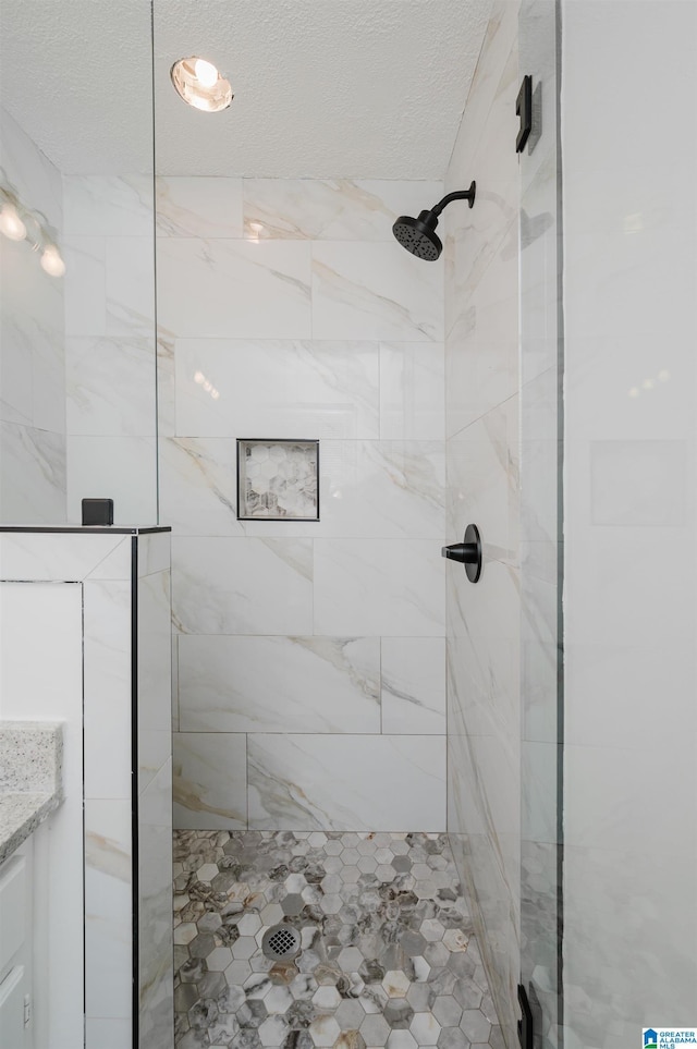 bathroom featuring tiled shower and vanity