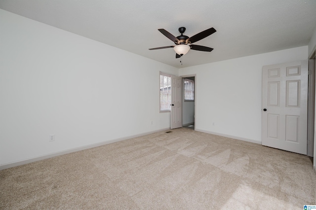 carpeted spare room featuring a textured ceiling and ceiling fan