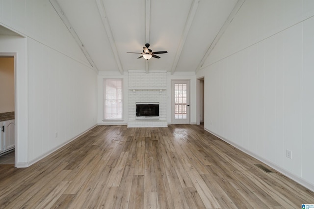 unfurnished living room featuring vaulted ceiling with beams, a fireplace, light hardwood / wood-style floors, and ceiling fan