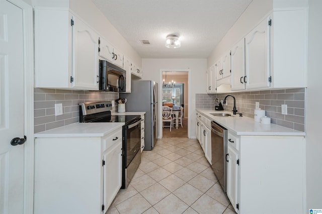 kitchen with sink, white cabinets, light tile patterned floors, stainless steel appliances, and a textured ceiling