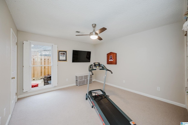 workout area featuring ceiling fan, light carpet, and a textured ceiling