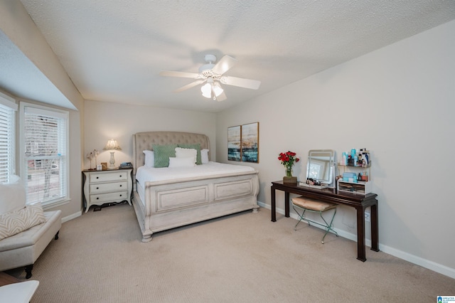 bedroom featuring ceiling fan, light colored carpet, and a textured ceiling