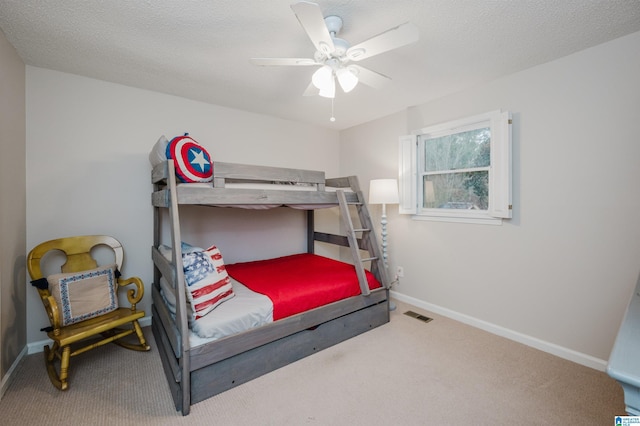 carpeted bedroom featuring ceiling fan and a textured ceiling