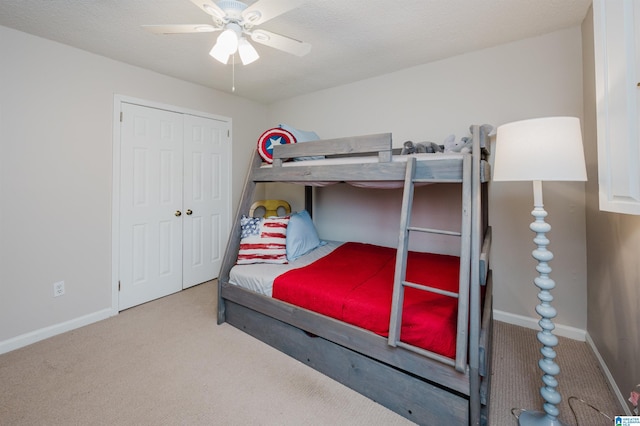 carpeted bedroom with ceiling fan, a closet, and a textured ceiling