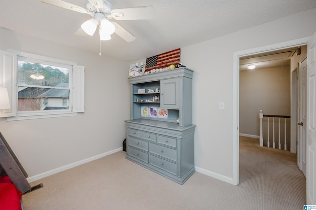 interior space featuring ceiling fan, light carpet, and a textured ceiling