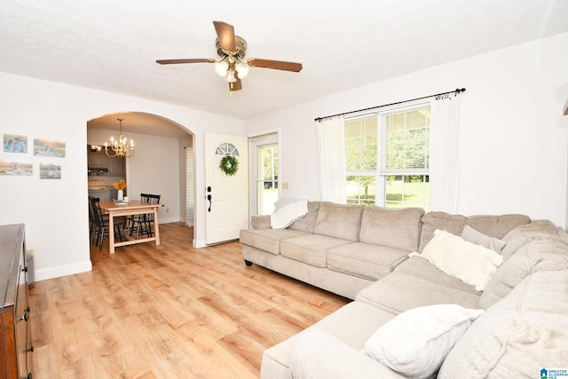 living room with ceiling fan with notable chandelier and light hardwood / wood-style flooring