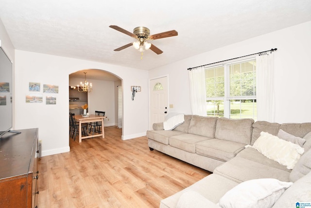 living room with ceiling fan with notable chandelier, light hardwood / wood-style floors, and a textured ceiling