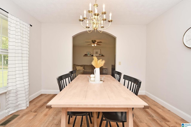 dining space with ceiling fan with notable chandelier and light wood-type flooring