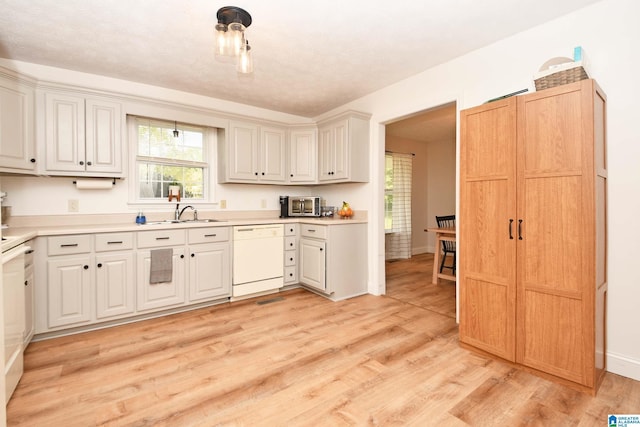 kitchen featuring dishwasher, sink, a textured ceiling, and light wood-type flooring