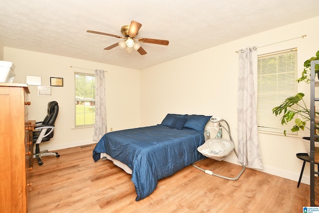 bedroom featuring ceiling fan, a textured ceiling, and light hardwood / wood-style flooring