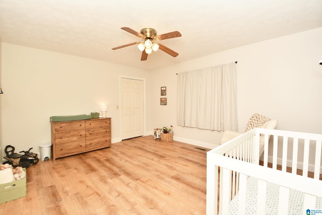 bedroom featuring hardwood / wood-style flooring, ceiling fan, and a nursery area