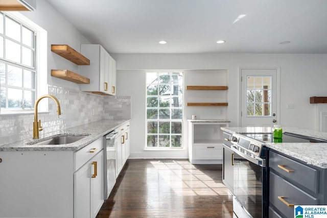 kitchen with light stone countertops, white cabinetry, appliances with stainless steel finishes, and sink