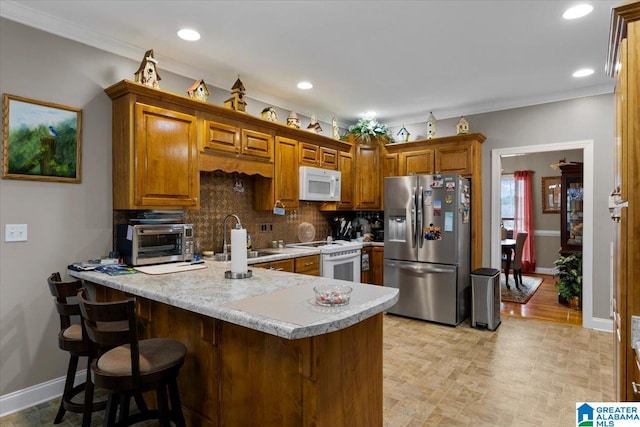 kitchen with a toaster, a peninsula, white appliances, a sink, and brown cabinets