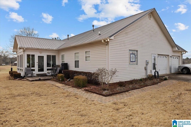 rear view of house featuring a yard, metal roof, concrete driveway, and french doors