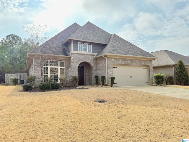 view of front of house with central AC, a garage, and a front lawn