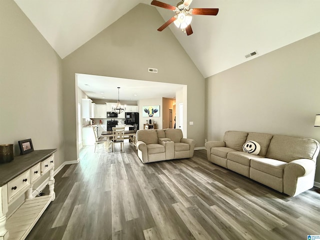 living room with high vaulted ceiling, dark hardwood / wood-style flooring, and ceiling fan with notable chandelier