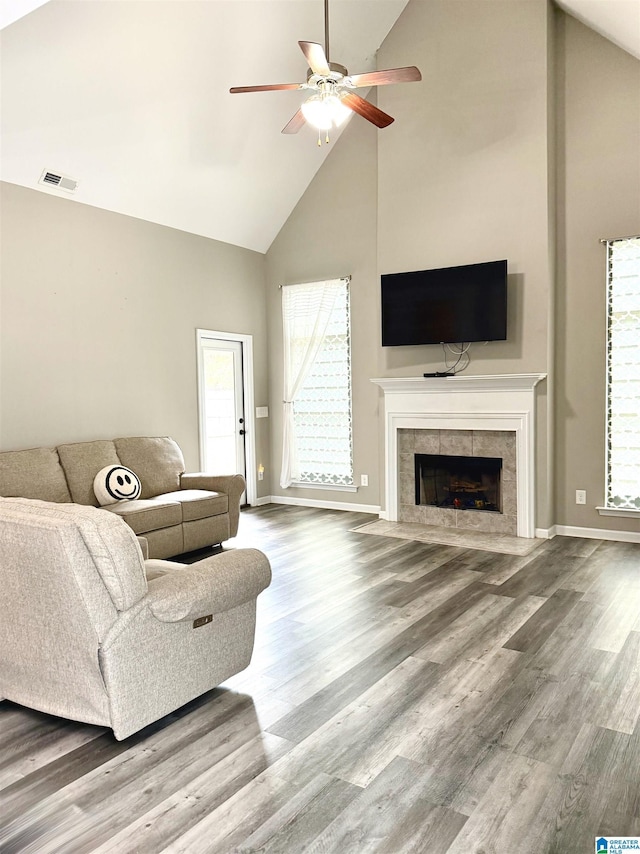 living room with a tile fireplace, wood-type flooring, ceiling fan, and high vaulted ceiling