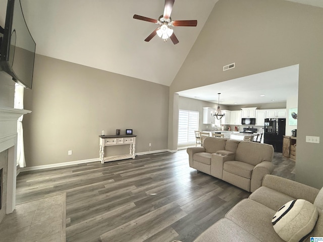 living room featuring high vaulted ceiling, ceiling fan with notable chandelier, and dark hardwood / wood-style flooring