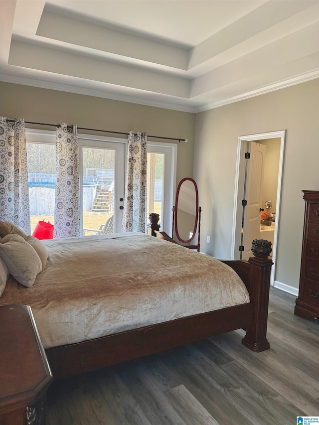 bedroom with dark hardwood / wood-style floors, access to outside, and a raised ceiling