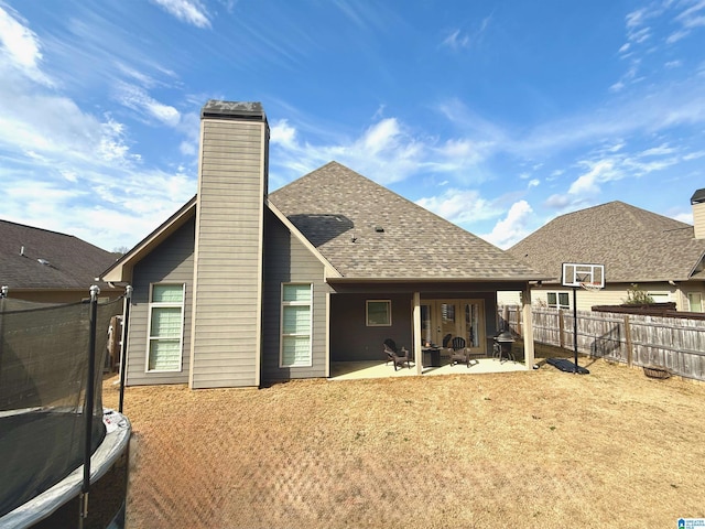 rear view of property featuring a trampoline and a patio area