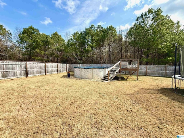 view of yard with a trampoline and a fenced in pool