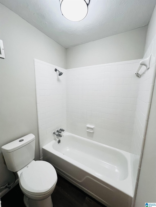 bathroom featuring tiled shower / bath, a textured ceiling, toilet, and hardwood / wood-style flooring