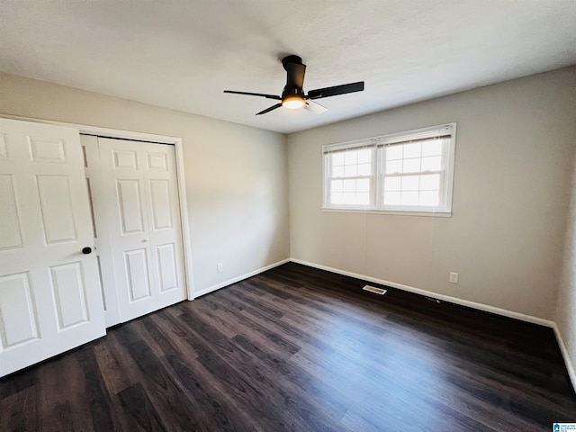 unfurnished bedroom with dark wood-type flooring, ceiling fan, and a closet