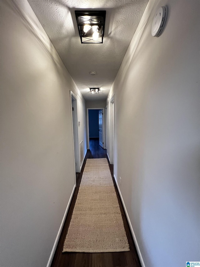 hallway featuring dark hardwood / wood-style flooring and a textured ceiling