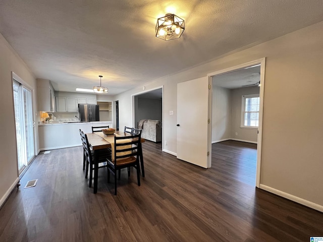 dining room with dark wood-type flooring and a textured ceiling