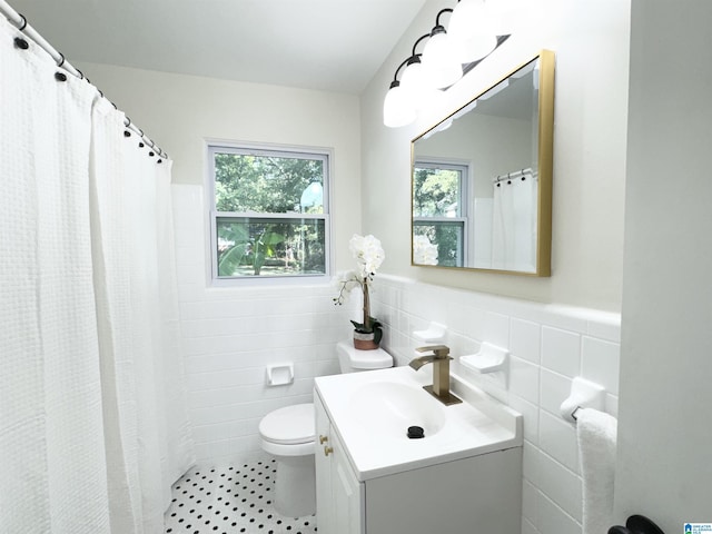 bathroom with vanity, curtained shower, toilet, and tile walls