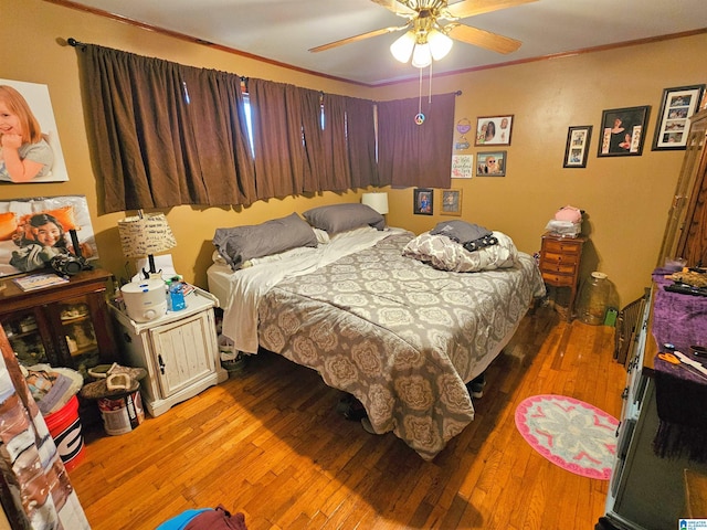 bedroom featuring hardwood / wood-style flooring, crown molding, and ceiling fan