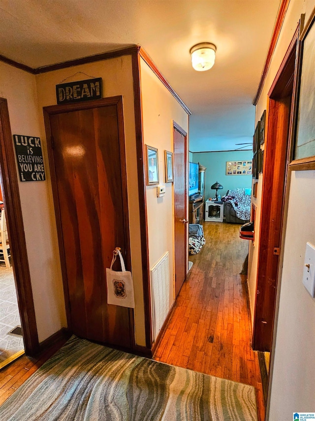 hallway with crown molding and hardwood / wood-style flooring