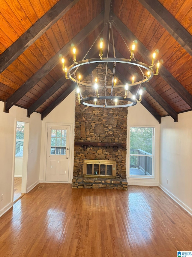 unfurnished living room with wood ceiling, vaulted ceiling with beams, a stone fireplace, and wood-type flooring