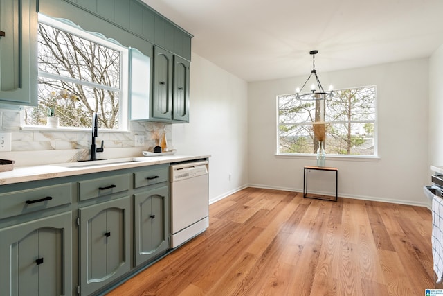 kitchen with dishwasher, sink, pendant lighting, and green cabinetry