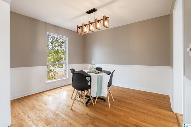 dining room with light hardwood / wood-style floors and a notable chandelier