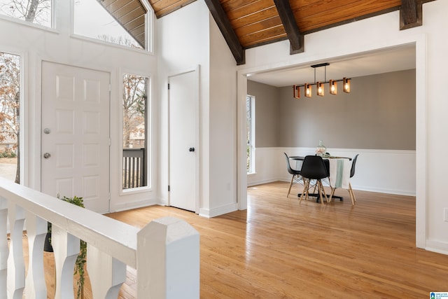 entrance foyer with beam ceiling, wooden ceiling, light hardwood / wood-style floors, and a healthy amount of sunlight