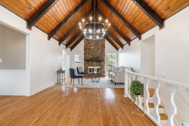 unfurnished living room featuring a stone fireplace, a notable chandelier, and wood ceiling