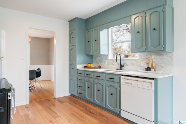 kitchen featuring white dishwasher, sink, decorative backsplash, and light hardwood / wood-style floors