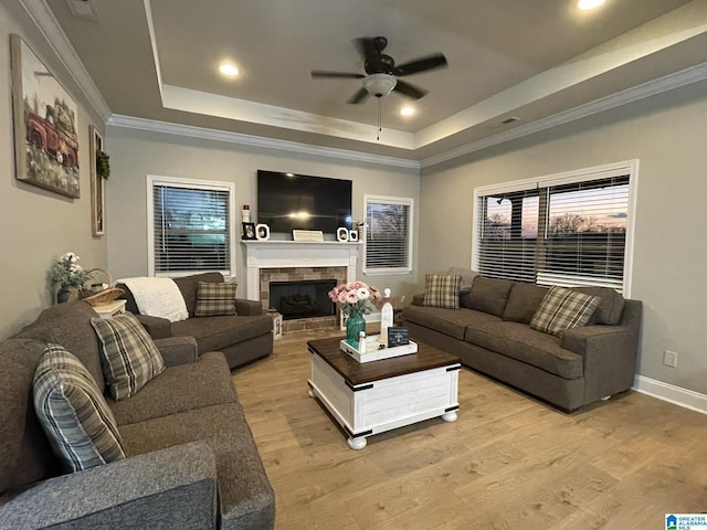 living room with ornamental molding, ceiling fan, light hardwood / wood-style floors, and a tray ceiling