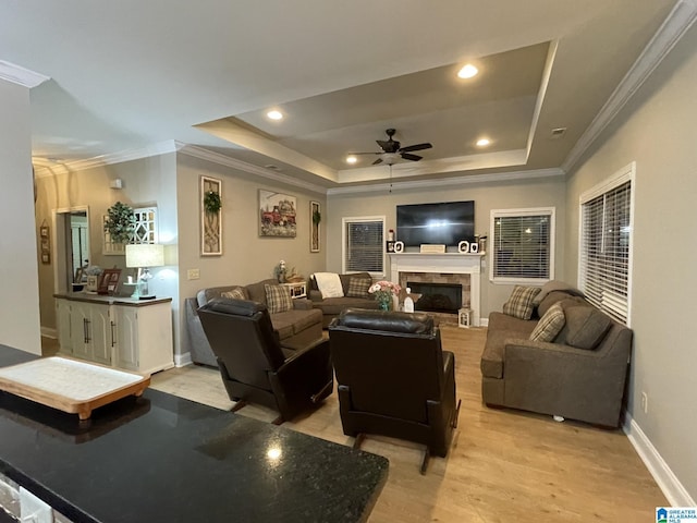 living room with a raised ceiling, ornamental molding, ceiling fan, and light hardwood / wood-style flooring