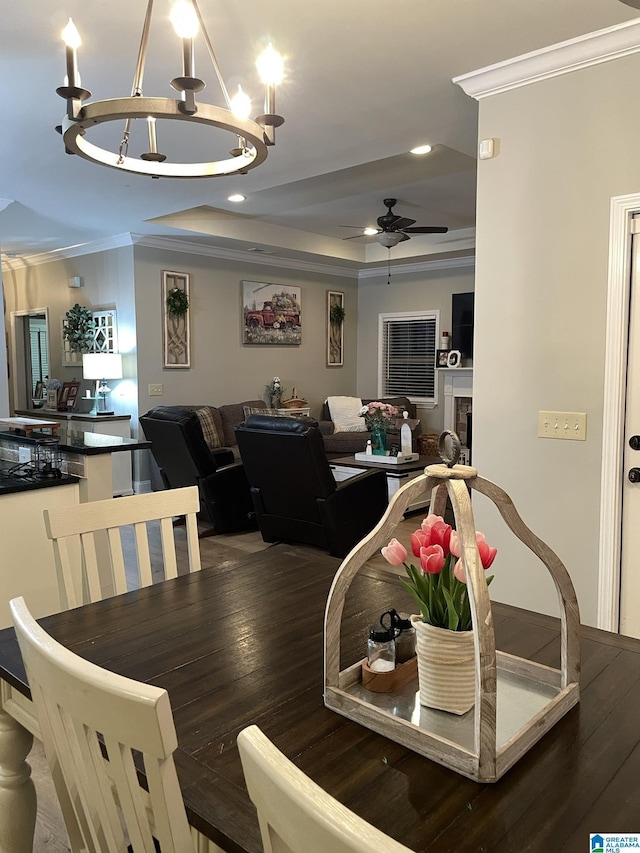 dining space featuring a tray ceiling, ornamental molding, dark hardwood / wood-style floors, and ceiling fan