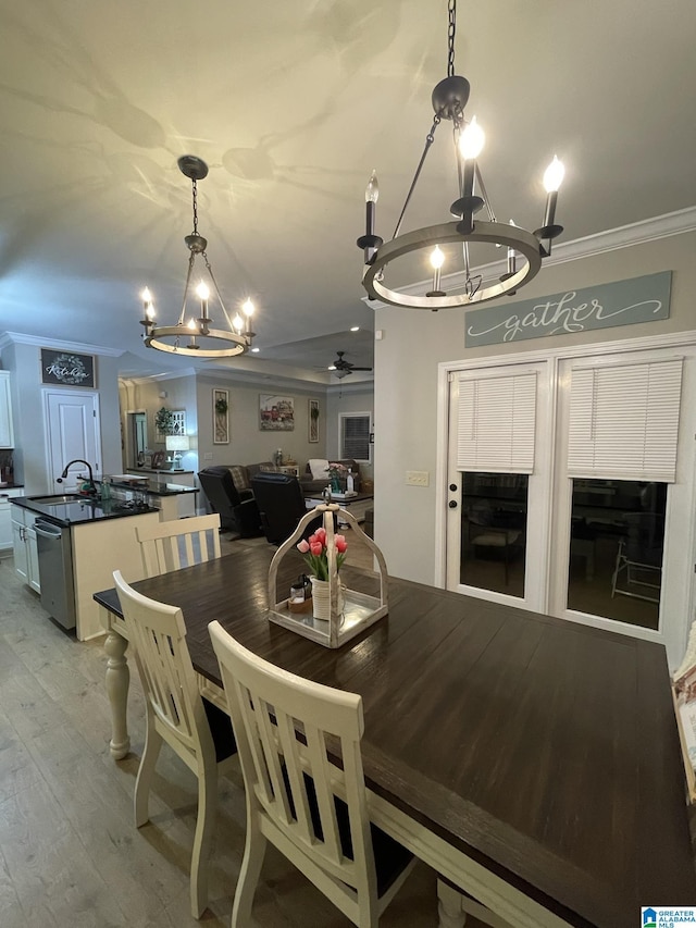 dining area with sink, crown molding, ceiling fan with notable chandelier, and light hardwood / wood-style floors