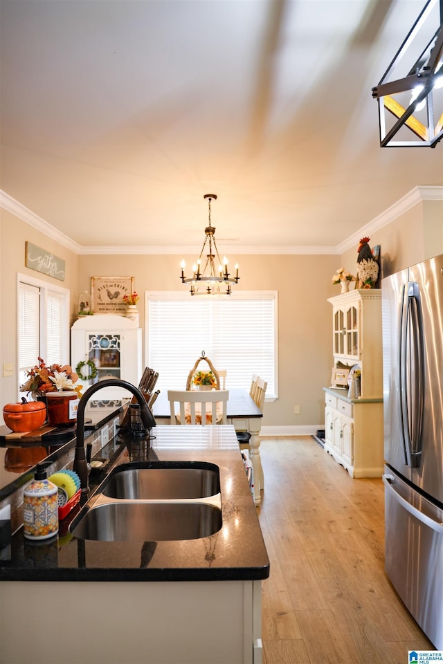 kitchen with pendant lighting, sink, stainless steel fridge, crown molding, and light hardwood / wood-style flooring