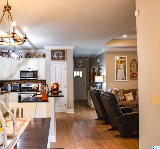 kitchen with pendant lighting, a kitchen bar, white cabinetry, and appliances with stainless steel finishes