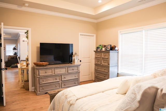 bedroom featuring crown molding, a tray ceiling, and light hardwood / wood-style flooring