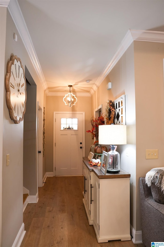 entryway with a notable chandelier, ornamental molding, and light wood-type flooring