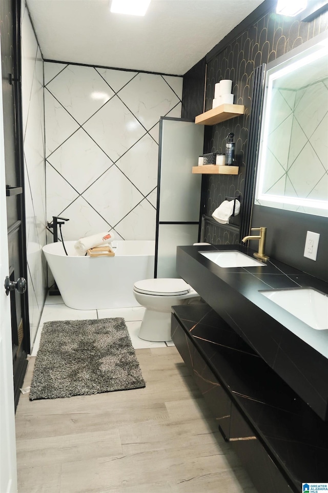 bathroom with a tub to relax in, toilet, tile walls, vanity, and hardwood / wood-style floors