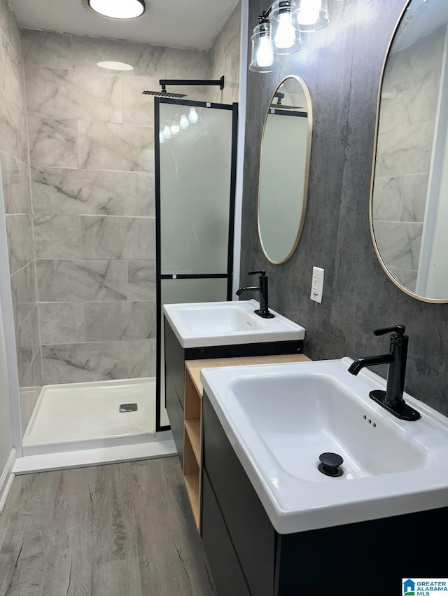 bathroom with wood-type flooring, vanity, and a tile shower