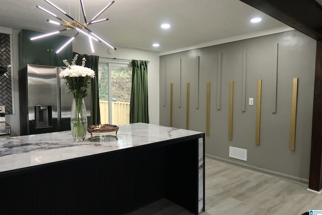 kitchen with light stone counters, a chandelier, light hardwood / wood-style flooring, and stainless steel refrigerator with ice dispenser