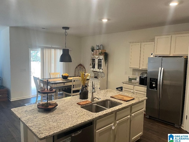 kitchen featuring stainless steel appliances, an island with sink, sink, and white cabinetry